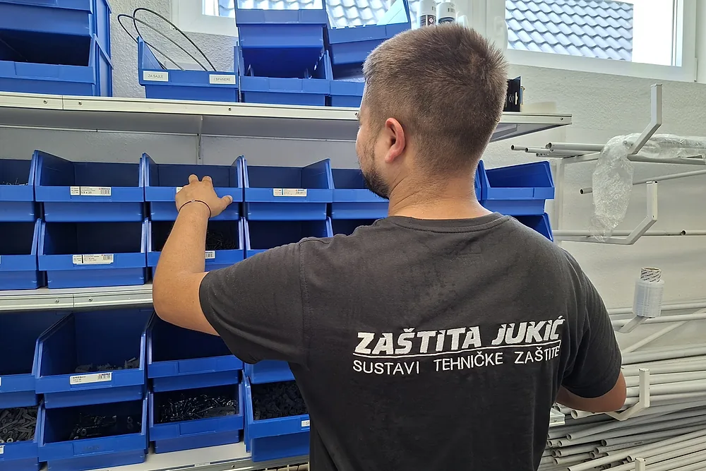 Tehničar Zaštite Jukić uzima montažni materijal iz police u skladištu